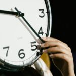 person holding white analog clock