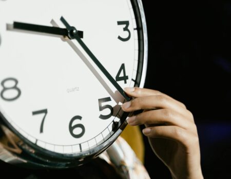 person holding white analog clock