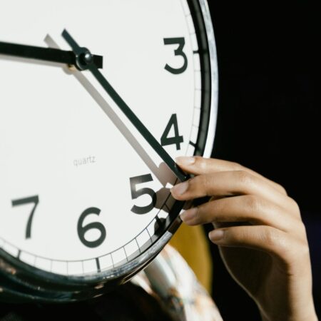 person holding white analog clock